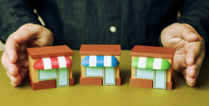 Tres locales de franquicia en miniatura entre las manos de una persona.
